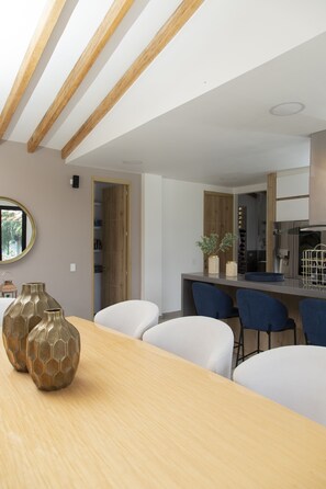 Enjoy meals in this dining area with a wooden table and four chairs, a large mirror, and a kitchen.