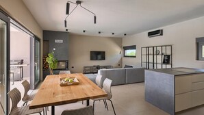 A modern kitchen with a wooden dining table, grey sofa, and a TV mounted on the wall. - Awesome home in Vodnjan (Vodnjan)