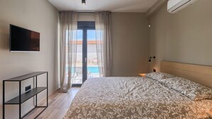 A hotel room with a bed, a TV, a bedside table, and a view of a pool. - Awesome home in Vodnjan (Vodnjan)