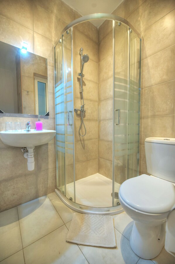 A modern bathroom with a glass-enclosed shower, a white sink, and a toilet.
