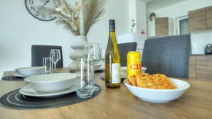 Une table à manger avec une bouteille de vin, une canette de bière et un bol de nourriture.