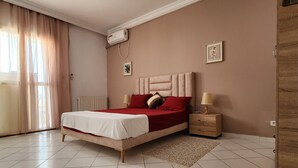 Une chambre à coucher comprenant un lit, des tables de chevet, un radiateur et un appareil de climatisation.
