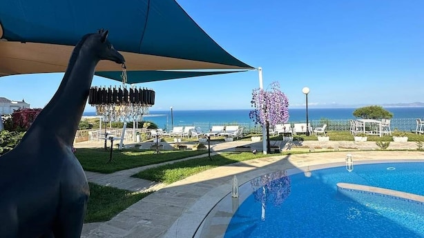 Un espace aménagé au bord de la piscine, avec une statue de girafe, une piscine et une vue sur l’océan.