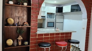Une cuisine avec un mur en briques, des étagères en bois et un pare-feu en miroir.