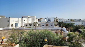 Un quartier résidentiel avec des bâtiments blancs, dont certains sont dotés de balcons, et un ciel d’un bleu éclatant.