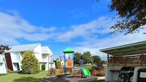 A playground with a slide and climbing structures, a picnic table, and a barbecue area. - Opuke Studio Methven (Methven)