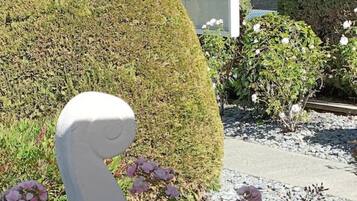 Un jardín con una escultura blanca, setos cuidadosamente podados y un edificio al fondo.