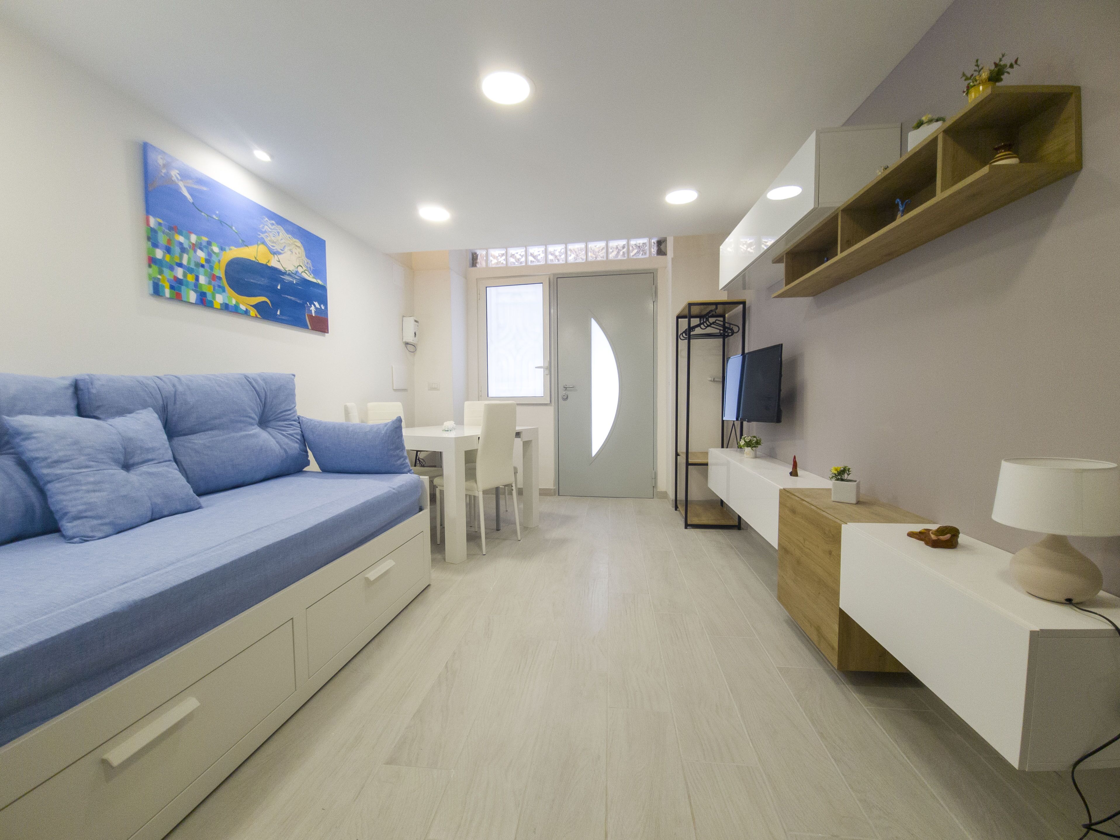 A modern bedroom with a bed, a desk, a TV, and a painting on the wall.