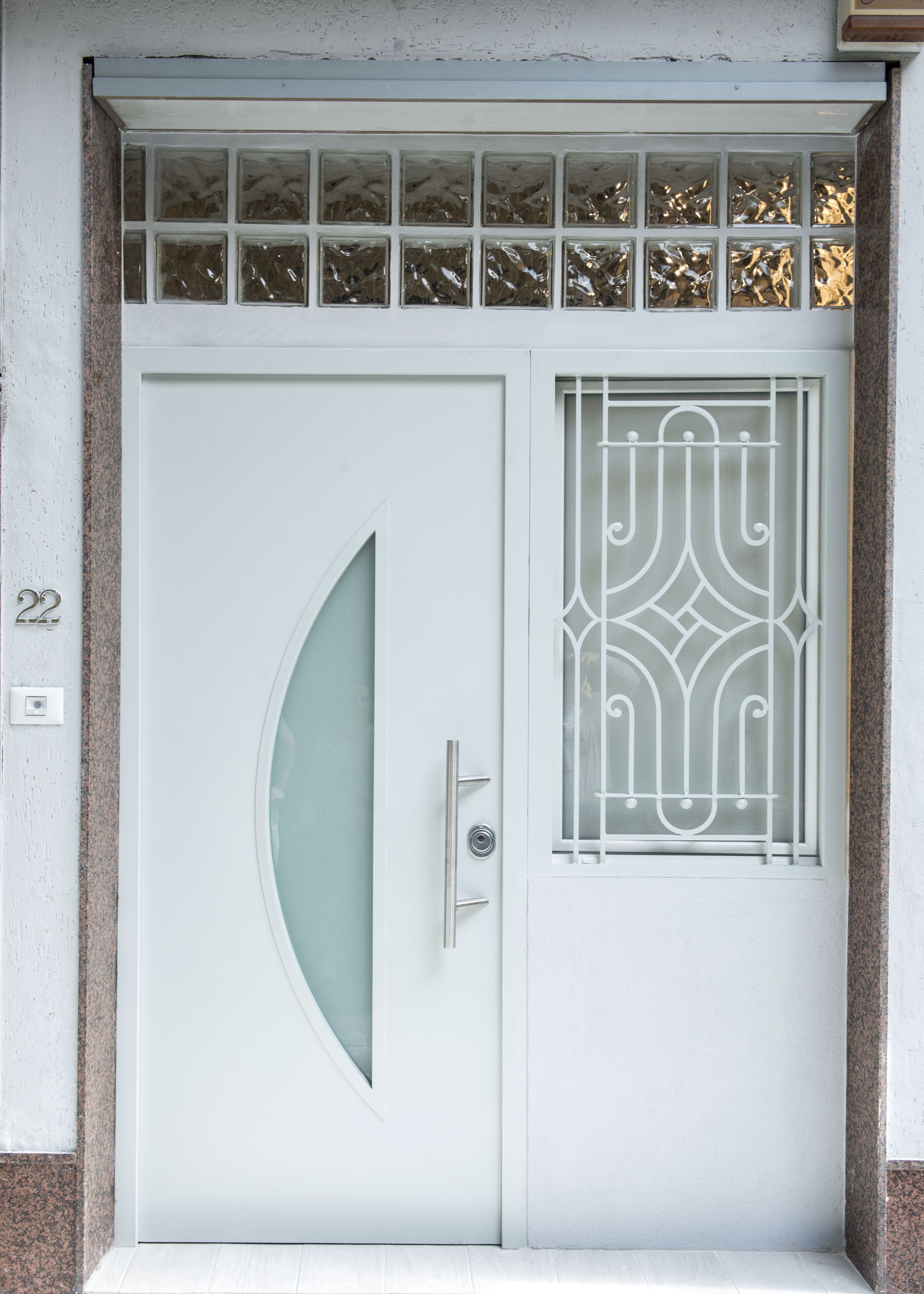 A white door with a curved glass panel and a decorative metal grille.