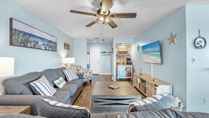 A living room with a grey sofa, a coffee table, and a ceiling fan. - Family waterfront condo,Dog Friendly, pools, boat launch, beach access, WIFI! (Gulf Shores)