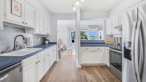 A modern kitchen with white cabinets, stainless steel appliances, and a blue countertop. - Family waterfront condo,Dog Friendly, pools, boat launch, beach access, WIFI! (Gulf Shores)