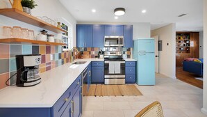 Uma cozinha moderna com armários azuis, micro-ondas de aço inoxidável e geladeira azul.