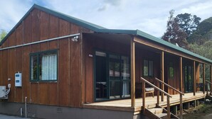 A rustic wooden building with a covered porch and a concrete pathway leading to the entrance.