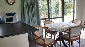 A kitchen with a microwave, a clock, and a window with curtains.