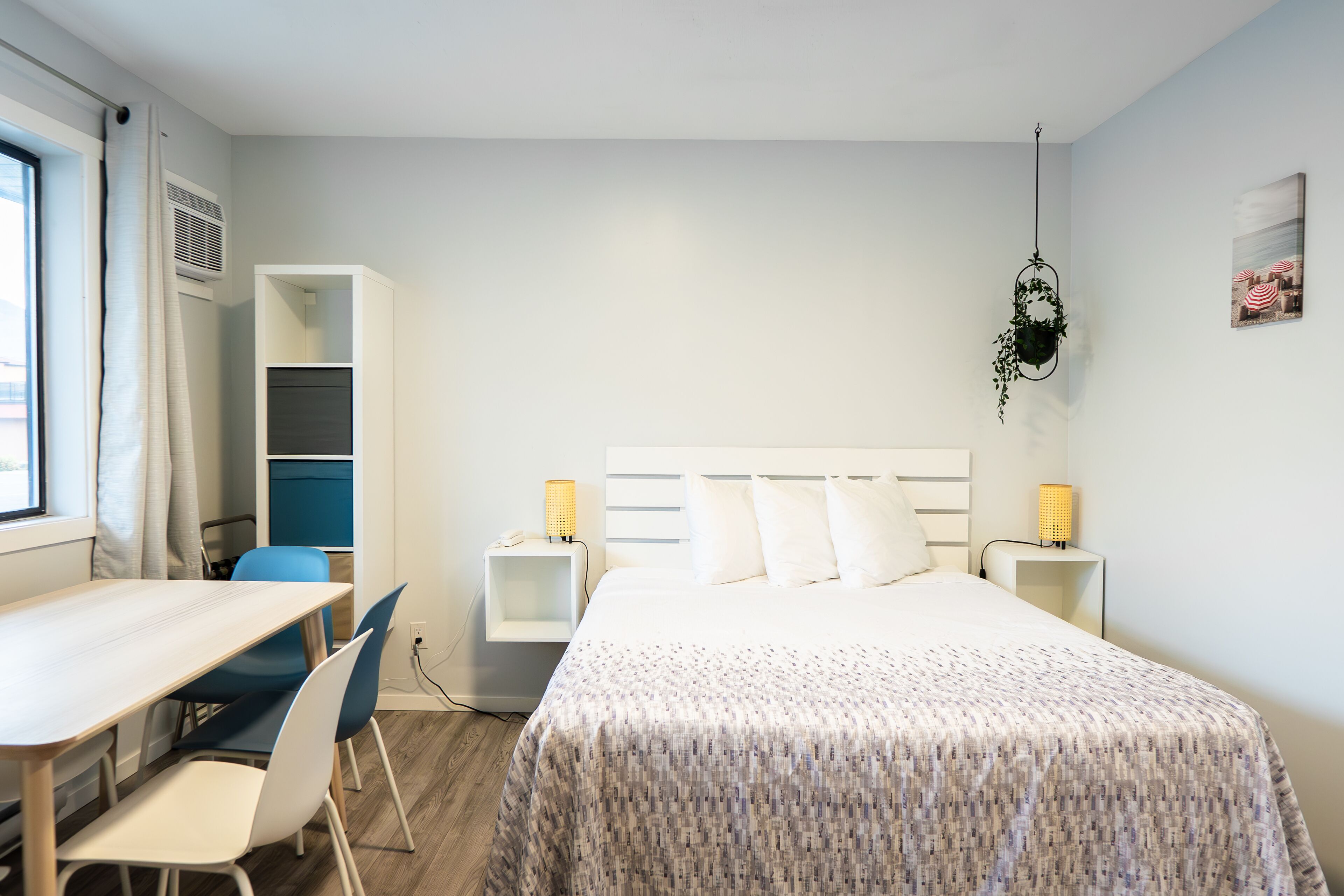 Une chambre à coucher comprenant un lit, des tables de chevet, un bureau, des chaises et une armoire.