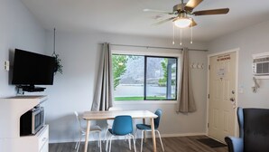 Una habitación moderna con una mesa de comedor, sillas, televisión y ventilador de techo.