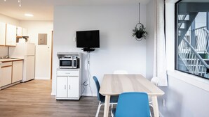 Una cocina moderna con armarios blancos, un microondas y un televisor de pantalla plana montado en la pared.