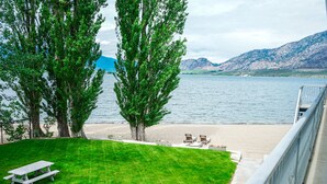 Un espacio verde con mesas de picnic y vistas a un lago y montañas.
