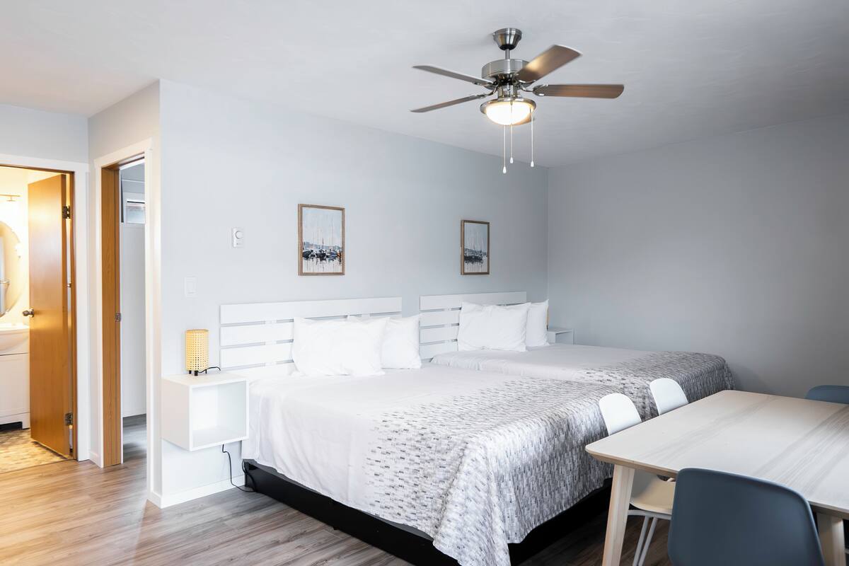 Una habitación de hotel con cama, mesitas de noche, escritorio y ventilador de techo.