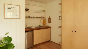 A kitchen with white cabinets, a wooden countertop, and a dishwasher. There are shelves with jars and kitchen utensils. - Romantic Cottage in the Blue Mountains with Valley Views (Hazelbrook)