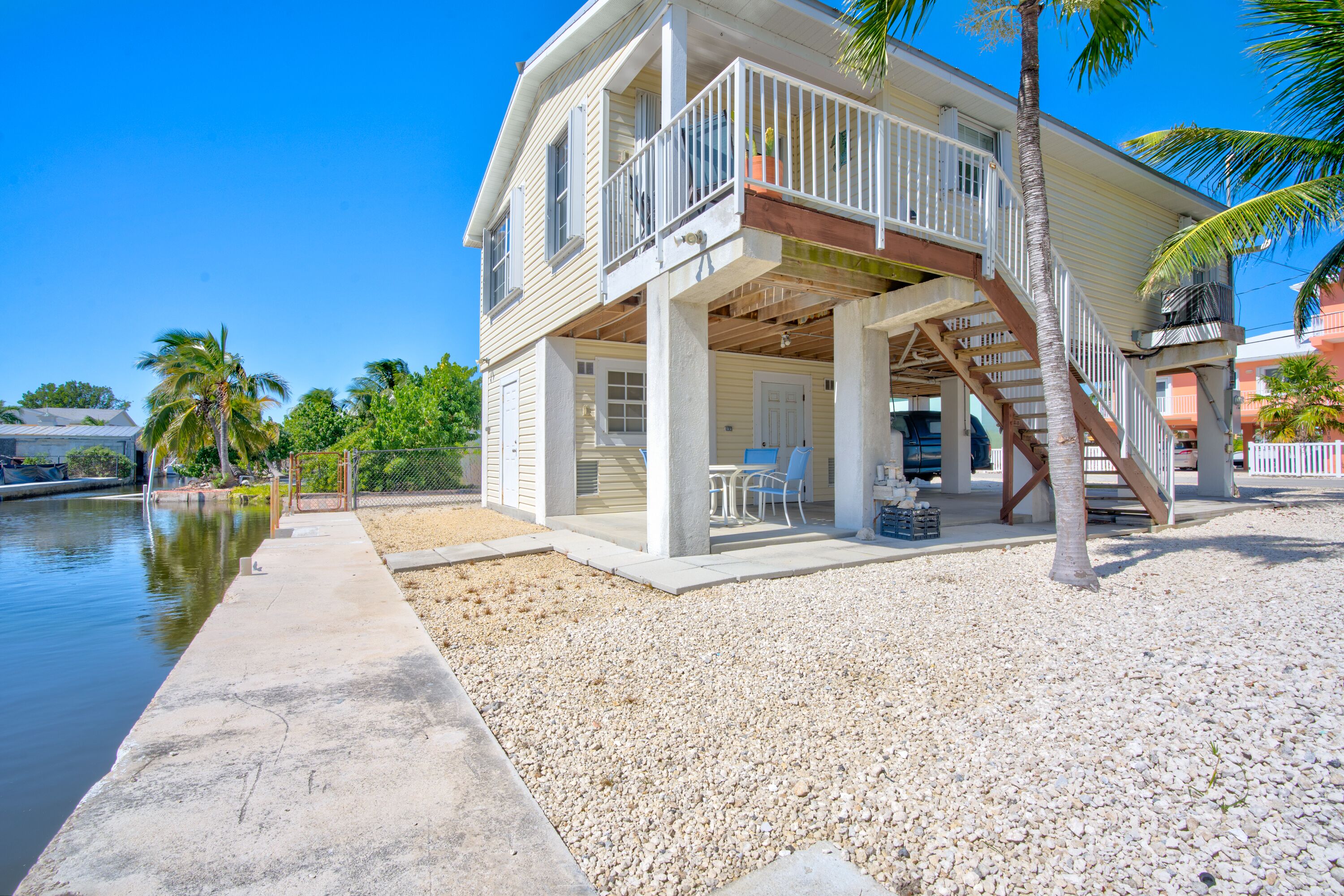 A two-story house with a balcony, a covered porch, and a view of the water.
