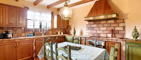 Una cocina con armarios de madera, una mesa de comedor y una chimenea de ladrillo.