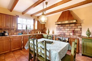 Une cuisine avec des meubles en bois, une table à manger et une cheminée en briques.