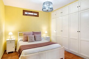 Une chambre à coucher comprenant un lit, des tables de chevet, une armoire et un lustre.