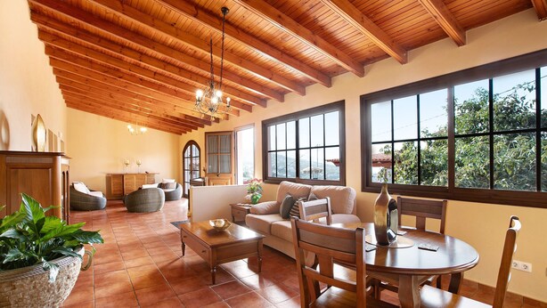 Un amplio salón con techo de madera, ventanas grandes y chimenea.