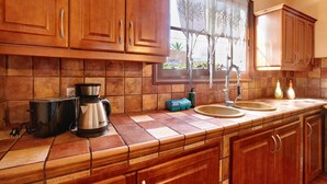 Una cocina con armarios de madera, cafetera, tostadora y ventana con vistas al exterior.