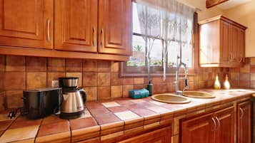 A kitchen with wooden cabinets, a coffee maker, a toaster, and a window with a view of the outside.