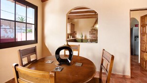 Una mesa de madera redonda con sillas, un florero y una ventana que da a vistas del exterior.