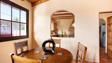 Een ronde houten eettafel met stoelen, een vaas en een raam met uitzicht op het exterieur.