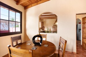 A round wooden dining table with chairs, a vase, and a window with a view of the outside. - Vacation Home 'Bonita Casa' with Sea View, Wi-Fi and Air Conditioning (La Victoria)
