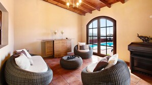 Habitación con muebles de mimbre, techo de madera, piscina y vistas.