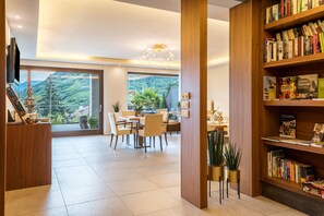 Una habitación amplia con comedor, estantería y un gran ventanal que ofrece vistas a un paisaje montañoso.