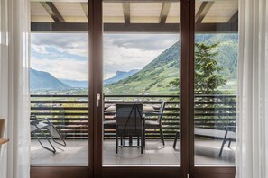 Een balkon met een tafel en stoelen, met uitzicht op een bergachtig landschap.