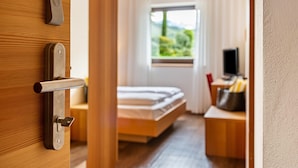 A hotel room with a wooden door, a bed, a desk, and a TV. - Apartment 'Alagundis  Pyropus Familia' with Mountain View, Shared Pool and Wi-Fi (Lagundo)
