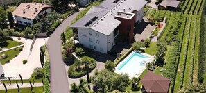 Un immeuble à plusieurs étages doté d’une piscine, entouré de jardins bien entretenus et d’un vignoble.