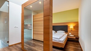 A modern bedroom with a wooden wardrobe, a bed with white linens, a bedside table with a lamp, and a glass partition. - Apartment 'Alagundis  Aurum II' with Mountain View, Shared Pool and Wi-Fi (Lagundo)