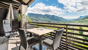 A balcony with wicker furniture, a table, and a view of mountains. - Apartment 'Alagundis  Aurum II' with Mountain View, Shared Pool and Wi-Fi (Lagundo)