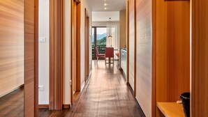 A hallway with wooden walls and a wooden floor, leading to a balcony with a red chair and a table. - Apartment 'Alagundis  Argentum Familia' with Mountain View, Shared Pool and Wi-Fi (Lagundo)