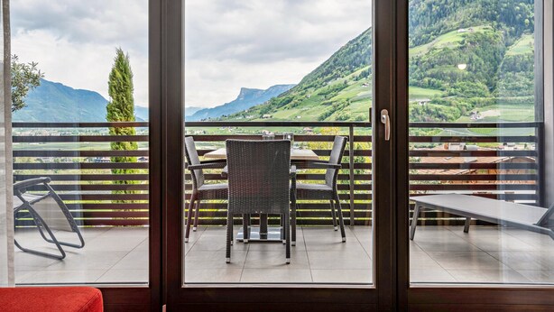 Varanda com mesa e cadeiras, proporcionando vista de uma paisagem montanhosa.
