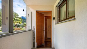 Corredor com porta de madeira identificada como '201 Argentina Familia', janela com vista para montanhas e um interfone.