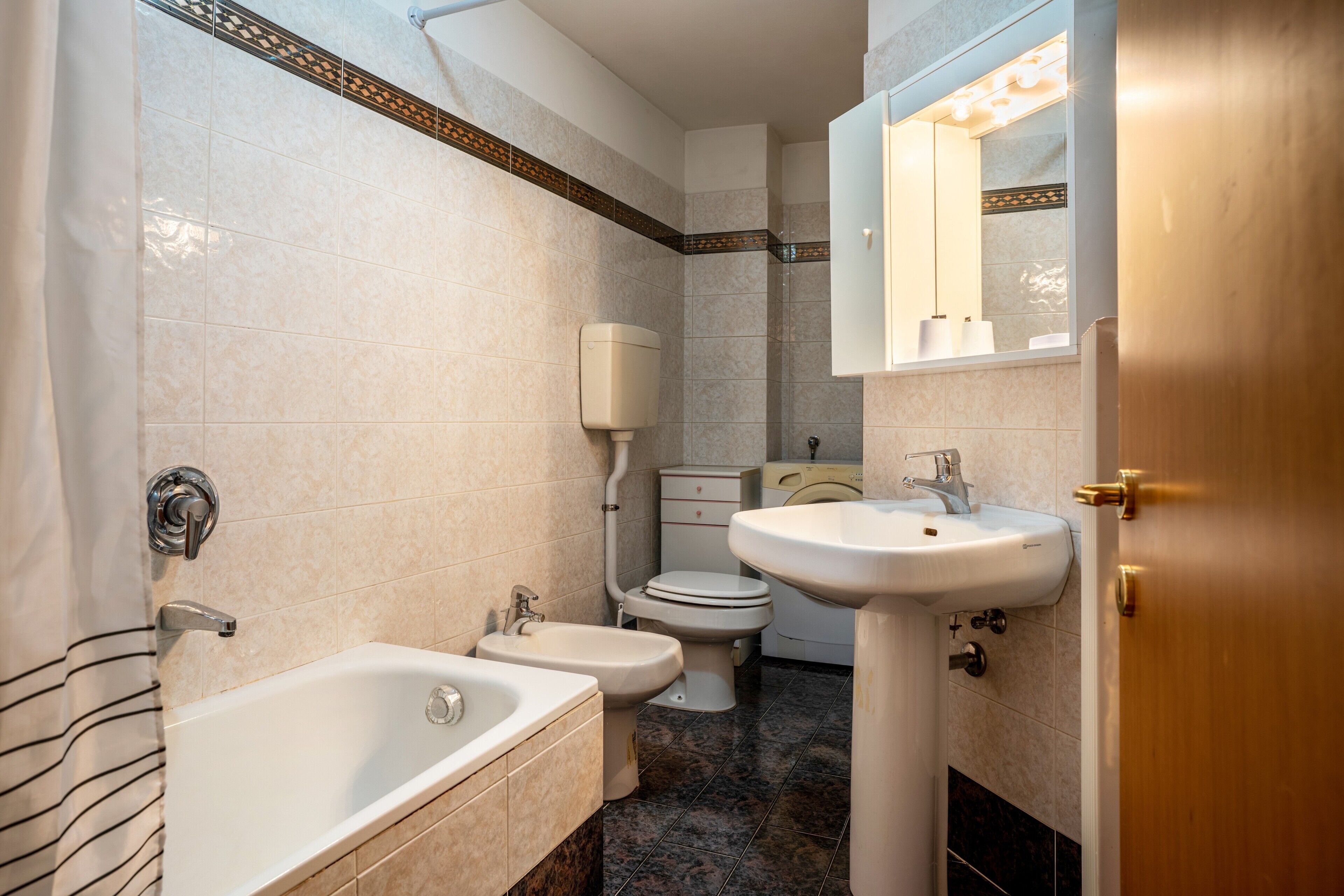 Une salle de bain avec une baignoire, deux toilettes, un lavabo et un miroir.