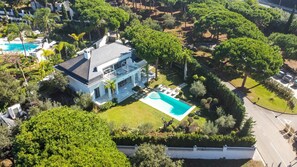 A large house with a swimming pool, surrounded by lush greenery and trees. - Villa 'Hacienda Las Chapas' with Private Pool, Wi-Fi and Air Conditioning (Marbella)