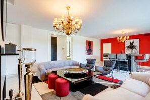 A modern living room with a chandelier, a sofa, a coffee table, and a dining area with chairs.