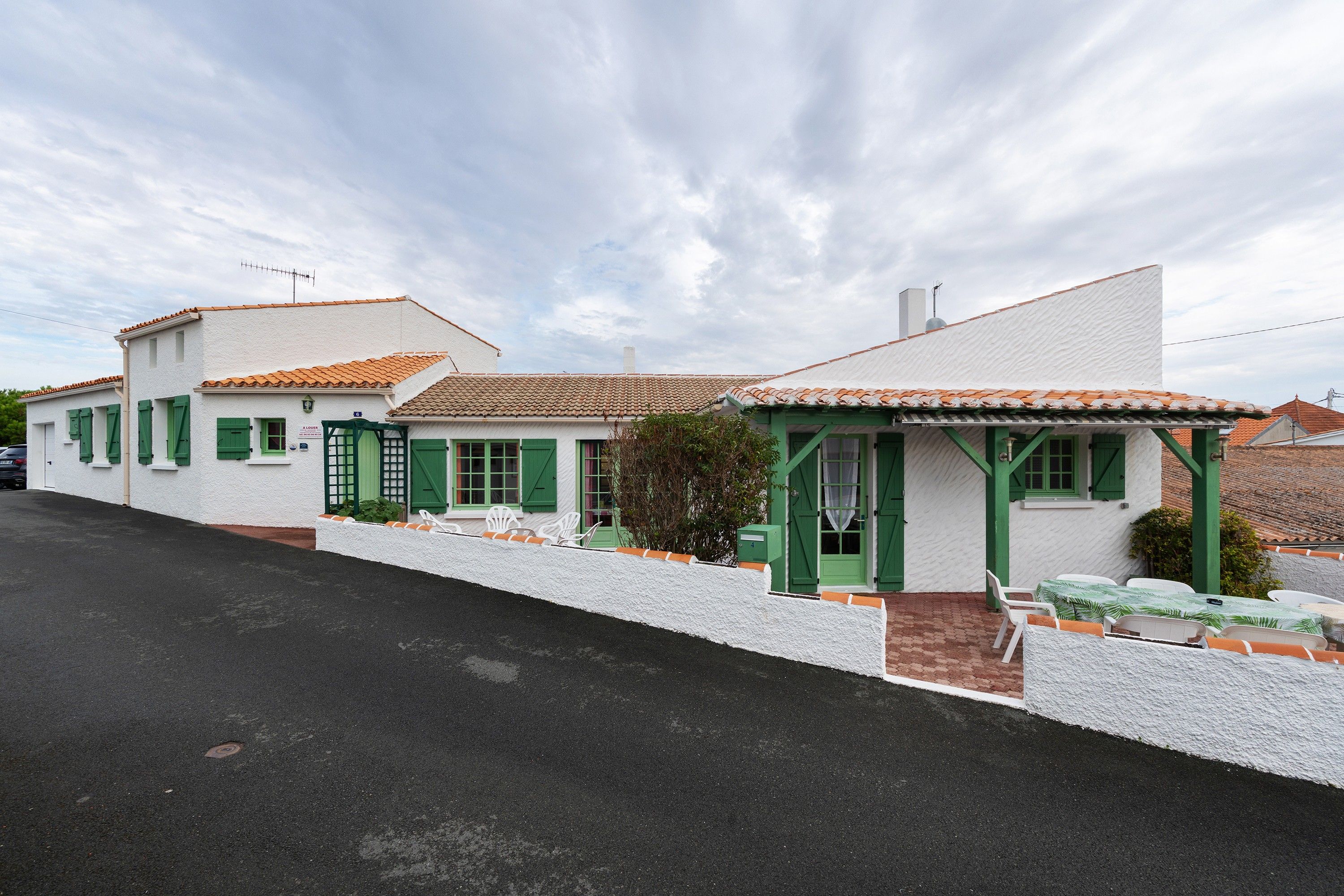 A row of white buildings with green shutters and a tiled roof.