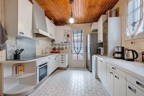 Een keuken met witte kasten, een houten plafond en een betegelde vloer.