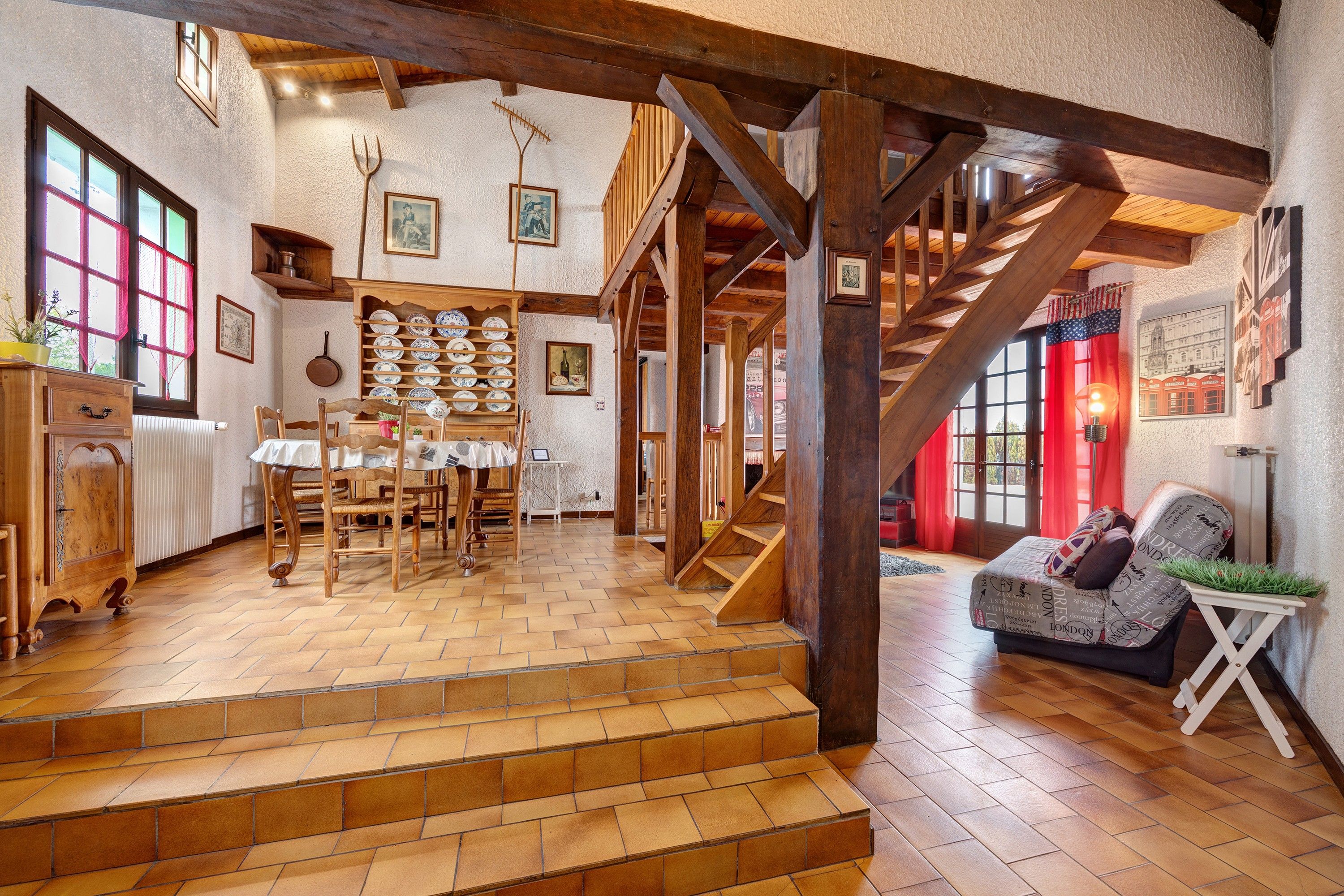 Un intérieur rustique avec des planchers en bois, un escalier, un coin repas avec une table et des chaises en bois, et un salon avec un canapé et une petite table.